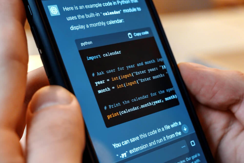 Hand holding a smartphone displaying ChatGPT-generated Python code for a calendar program.